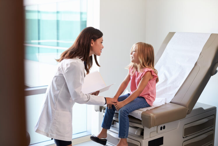 Pediatrician In White Coat With Child In Exam Room